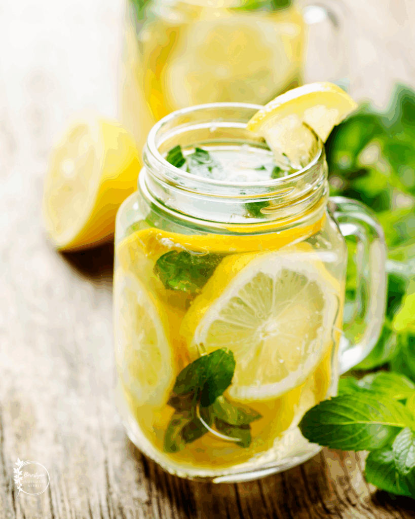 Üvegkorsóban tálalt mentás limonádé citromkarikákkal és friss mentalevelekkel.