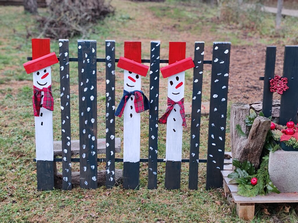 Hóemberes kerítéselem a karácsonyi lámpaoszlop mellett, megmaradt korlátból készült kerti dekorációként