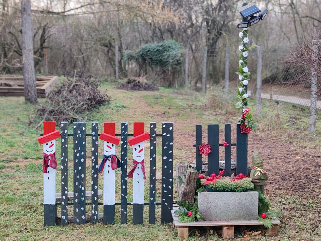 Hóemberes kerítéselem és karácsonyi lámpaoszlop együtt, megmaradt korlátból készült kültéri karácsonyi dekorációként.
