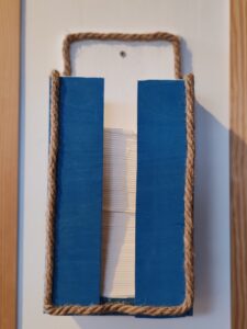 Kék-fehér színű, kötéllel díszített fa papírzsebkendő tartó falra szerelve